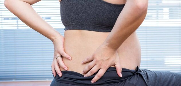 A woman in advanced pregnancy, just before giving birth, performs loosening exercises to facilitate preparation for childbirth. Expectant mother dressed in sports outfit sits on a large ball and props with her hands in the lumbar spine.