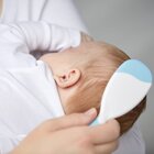 The mother hugs the baby and gently combs the hair with a soft brush. Care for both the baby's scalp and hair is very important.