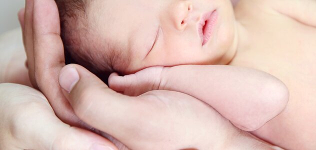 The infant sleeping peacefully with a handle under its head. The child lying on the hands of parents who is holding him gently. Childcare is a multi-stage and complex process.